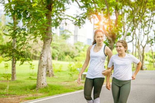 Hintli kadın yoga öğretmeni ve sekiz yaşındaki öğrenci parkta sabah yürüyüşü için birlikte yürüyüp konuşuyorlar. sağlık ve zindelik kavramı