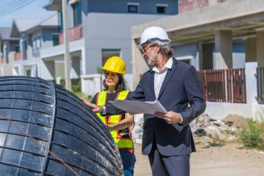 İnşaat alanında panosu olan kasklı genç mühendis.