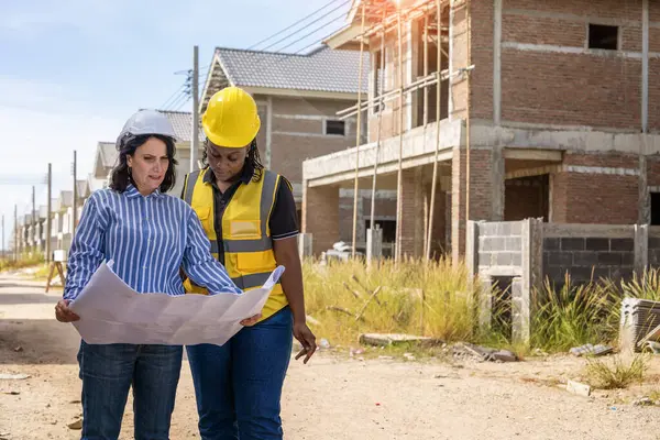 african american architect and engineer woman wearing yellow helmet, construction engineer woman and construction worker at construction site