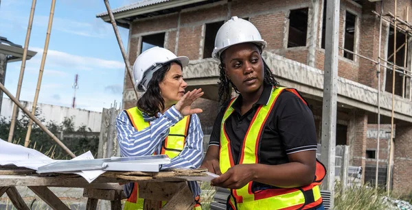 Successful and construction work Concept.female architect, inspecting work with african american engineer talking, consulting together and serious work not finished according to plan on housing construction project.