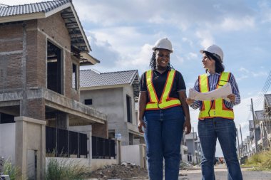 Başarılı ve inşaat işi konsepti. Kadın mimar, Afro-Amerikan mühendis ile iş görüşmesi, birlikte danışmanlık ve konut inşaatı inşaatı için planlanan ciddi işler..