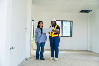 Başarılı ve inşaat işi konsepti. Kadın mimar, Afro-Amerikan mühendis ile iş görüşmesi, birlikte danışmanlık ve konut inşaatı inşaatı için planlanan ciddi işler..