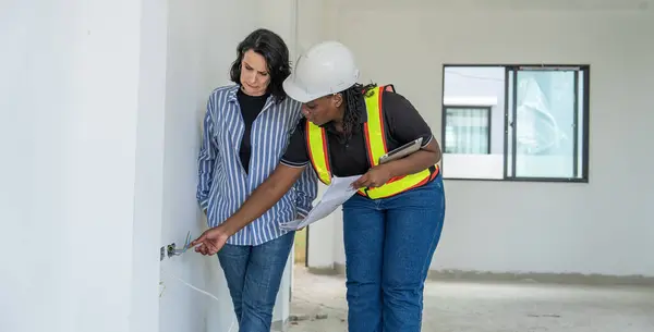 Successful and construction work Concept.female architect, inspecting work with african american engineer talking, consulting together and serious workfinished  to plan on housing construction project site.
