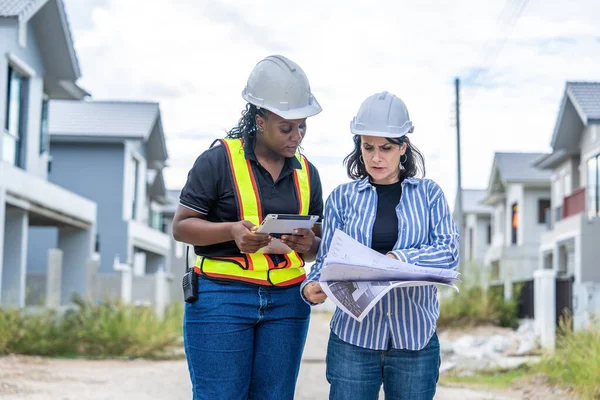 Successful and construction work Concept.female architect, inspecting work with african american engineer talking, consulting together and serious workfinished  to plan on housing construction project site.
