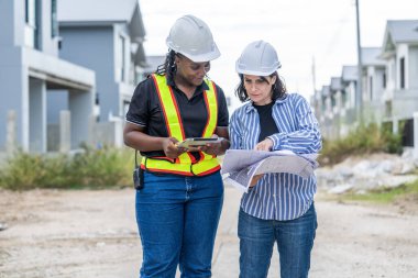 Kadın inşaat mühendisi ve erkek mimar inşaat alanında planlarını tartışıyorlar. Yeni evde çalışan inşaat mühendisi.