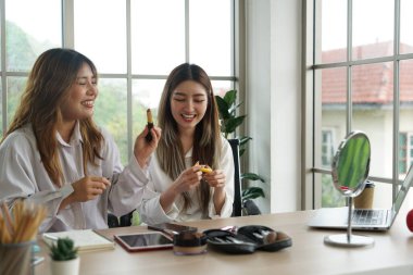 İki genç Asyalı blogcu, internette kozmetik satan ev arkadaşları, dairelerinde akıllı telefonlar ve dizüstü bilgisayarlar kullanarak pudra, ruj, fırça ve makyaj eleştirileri öneriyorlar..