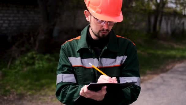 Ingenieur Een Beschermende Helm Maakt Vermeldingen Een Tijdschrift — Stockvideo