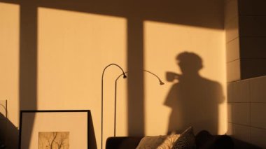 shadow on the wall from a man drinking tea