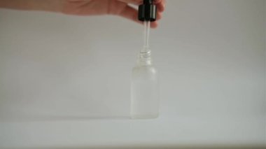 woman hand takes out a pipette with cosmetic face serum from a glass jar mockup