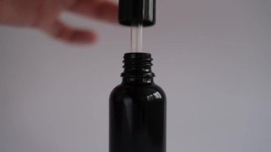 woman hand takes out a pipette with cosmetic face serum from a glass jar mockup