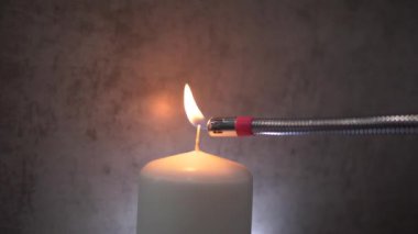 a man with an electric lighter ignites the wick of a candle close-up