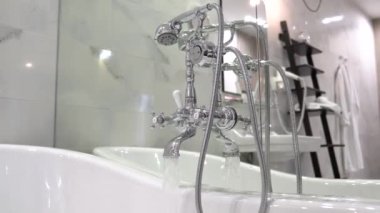 open faucet drawing water into a bathtub in a luxurious bathroom interior