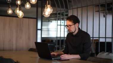 Modern bir ofiste dizüstü bilgisayarda online toplantı düzenleyen bir iş danışmanı.
