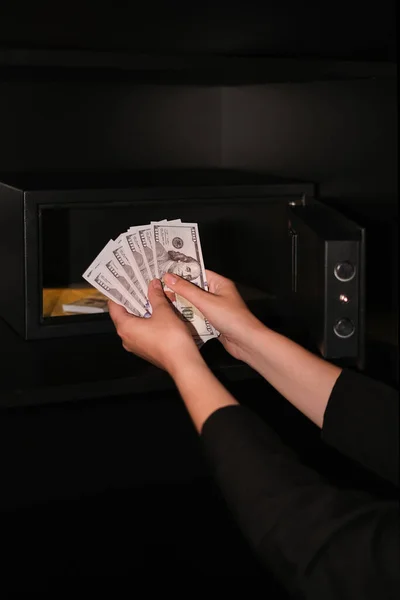 a woman counts money against the background of a safe close-up of hands