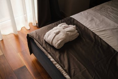 Yatağın kenarında katlanmış beyaz bornoz.