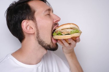 Beyaz arka planda hamburger yiyen beyaz bir adamın portresi.