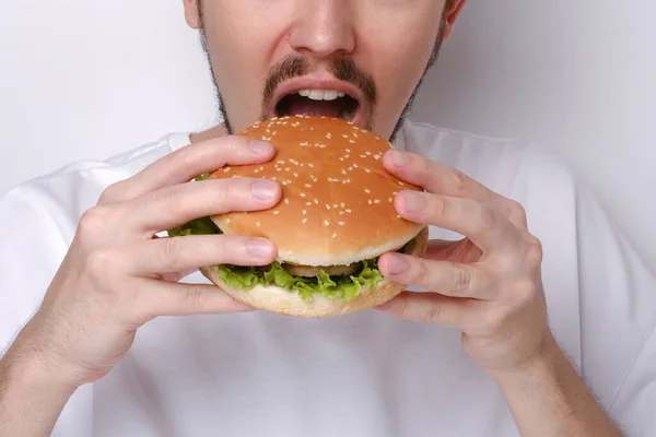 Portrait of a Caucasian man eating a burger on a white background