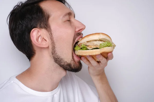 Portrait of a Caucasian man eating a burger on a white background