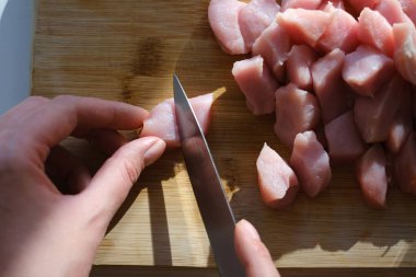 Kadın kesme tahtasıyla tavuk filetosu kesiyor.