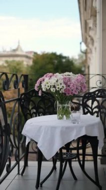 Teras masasında bir bardak çiçekle bir bardak su.