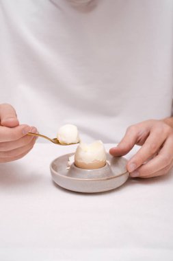 Bir adam kahvaltıda yumurta yer. Haşlanmış bir kâsede.