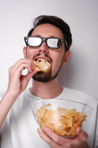 3Dメガネで映画を見てチップを食べている若者の肖像画 ストック画像