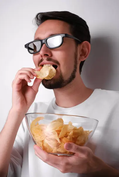 3Dメガネで映画を見てチップを食べている若者の肖像画 ストックフォト
