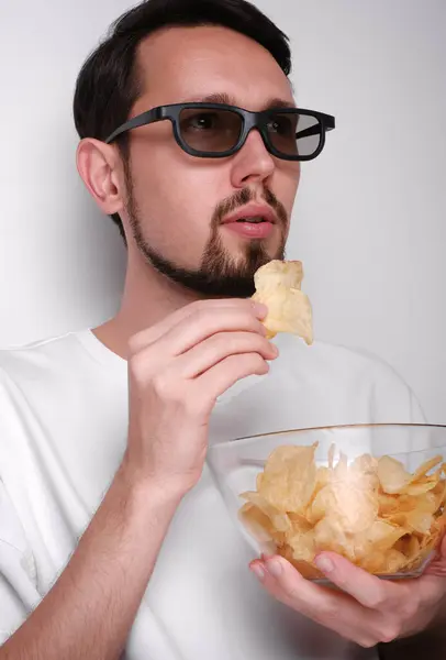 3Dメガネで映画を見てチップを食べている若者の肖像画 ロイヤリティフリーのストック写真