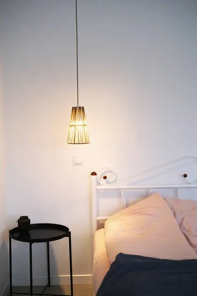 スカンジナビアスタイルのベッド ペンダントランプ ベッドサイドテーブルの明るい寝室のモダンなインテリア ストック画像