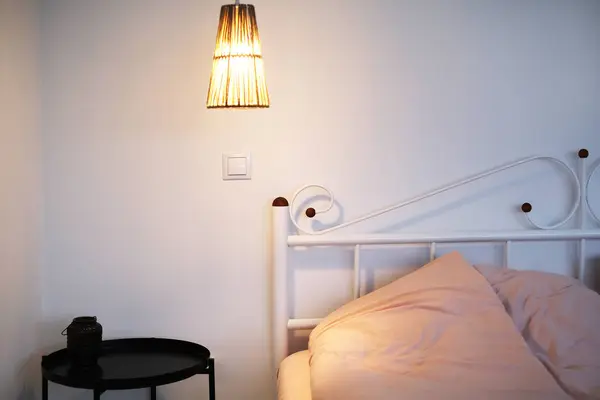 スカンジナビアスタイルのベッド ペンダントランプ ベッドサイドテーブルの明るい寝室のモダンなインテリア ロイヤリティフリーのストック写真