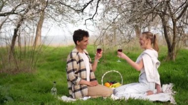 Genç ve güzel bir çift piknikte şarap içip gülüyorlar.