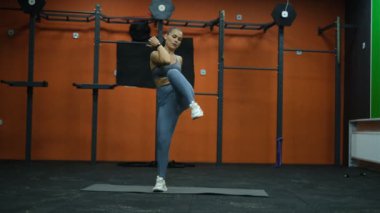 Güzel kaslı sporcu kadın spor salonunda dururken karın egzersizi yapıyor.