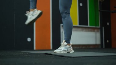 Güzel kaslı sporcu kadın ayak bileği ısınma egzersizleri yapıyor. Spor salonunun yakın plan bacaklarında.
