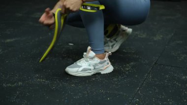 Güzel kaslı sporcu kadın spor olsun diye bacaklarına ağırlık koyuyor.