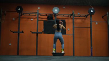 Güzel kaslı sporcu kadın, jimnastik topunun arkasında dururken topu fırlatıyor.