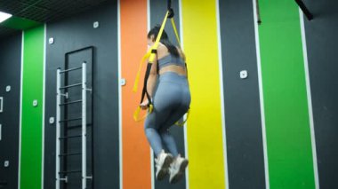 Güzel sporcu kadın spor salonunda trakeoskopla çalışıyor.