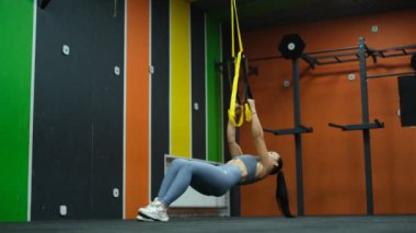 Güzel sporcu kadın spor salonunda trakeoskopla çalışıyor.
