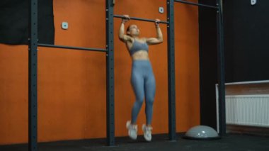 Güzel genç sporcu kadın spor salonundaki barda takla atıyor.