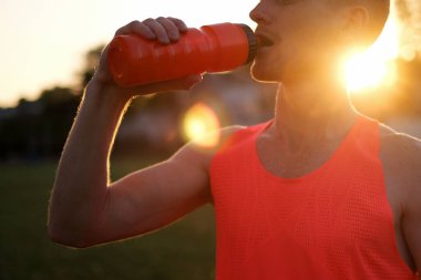 Atletizm sporcusu stadyumda idmandan sonra su içiyor.