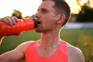 track and field athlete drinking water after training at the stadium clipart