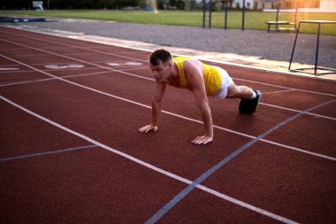 Koşmadan önce stadyumda şınav çeken bir sporcu.
