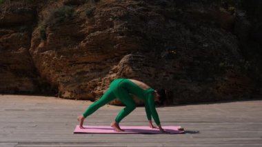 Yoga eğitmeni egzersizleri açık havada bir minder üzerinde gösteriyor.