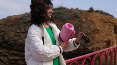 Genç zayıf sporcu yoga minderine güneş gözlüğü takıyor.