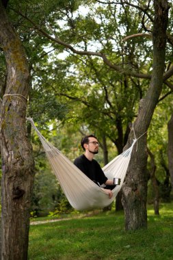 Genç adam deniz kenarındaki bir hamakta dinleniyor.