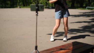 Sosyal ağlar için telefonuna video çeken parkta dans eden genç bir kadının portresi.