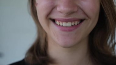 Güzel düz dişleri olan genç bir kadının gülümsemesi, yakın plan.