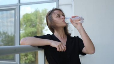 Güneşli bir yaz gününde bir şişeden su içen güzel bir kadının portresi.