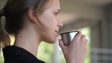 Genç ve güzel bir kadın meditasyondan sonra termostan çay içer.