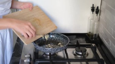 Genç bayan sarımsak kızartır, tavada yakın plan ellerde.
