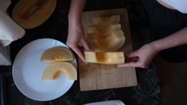 Genç bir kadın dilimlenmiş kavunu tabağa koyuyor.